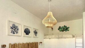 Une chambre à coucher avec un lit, une tête de lit en bois, un luminaire suspendu, des œuvres d’art accrochées au mur et une échelle.