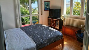 Une chambre avec un lit, une télévision, un radiateur et une vue sur la verdure.