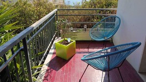 Un balcon avec vue sur la mer, une chaise bleue et un jardinier.