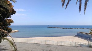 Une plage avec un ciel dégagé, un rivage sablonneux et une digue rocheuse.