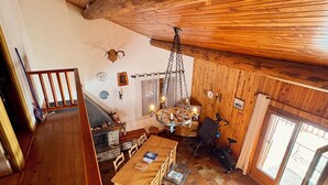 Un interior de madera con una mesa de comedor, sillas, una lámpara colgante y una chimenea.