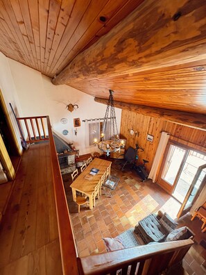 Ein Holzinterieur mit einem Esstisch, Stühlen, einer Hängeleuchte und einem Kamin.