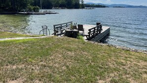 A lakeside park with a wooden dock, benches, and a flagpole. - Exceptional Lakefront Home on Springfield Point – Lake Winnipesaukee (Wolfeboro)