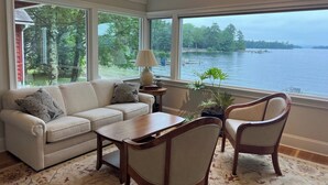 A room with a sofa, chairs, a table, and a view of a lake. - Exceptional Lakefront Home on Springfield Point – Lake Winnipesaukee (Wolfeboro)