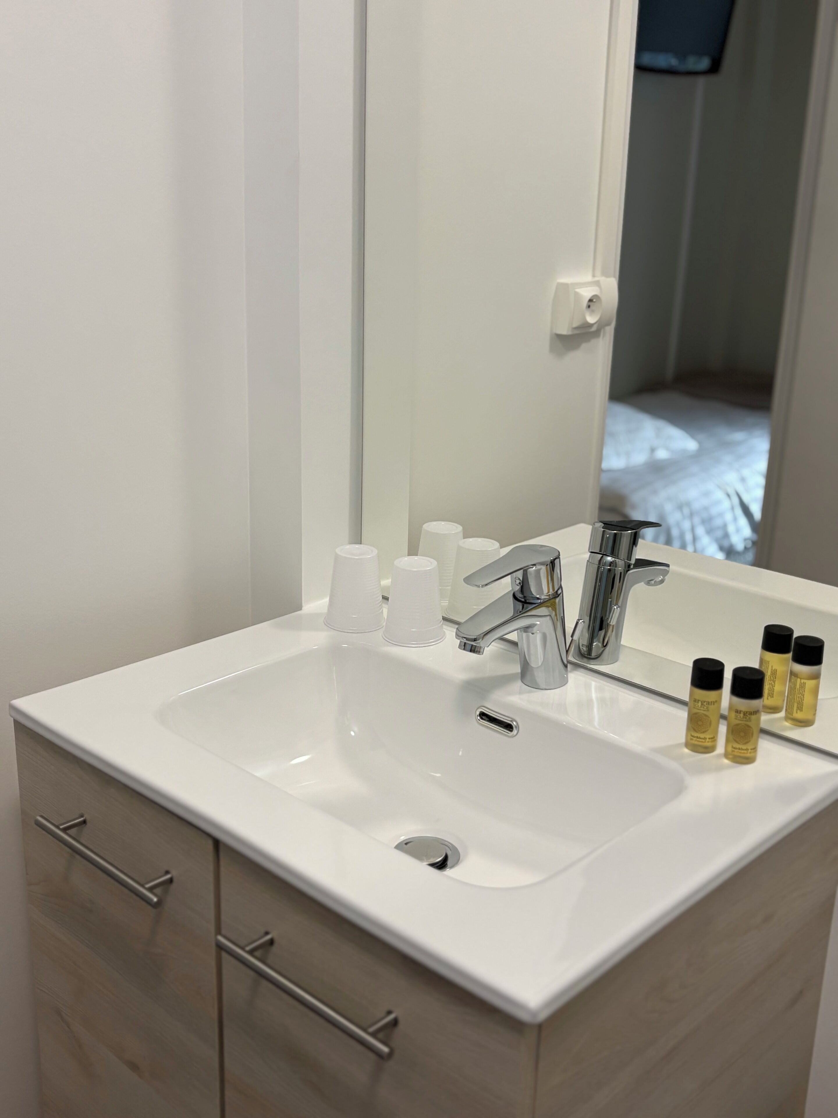 A bathroom with a white sink, a mirror, and a cabinet with drawers.