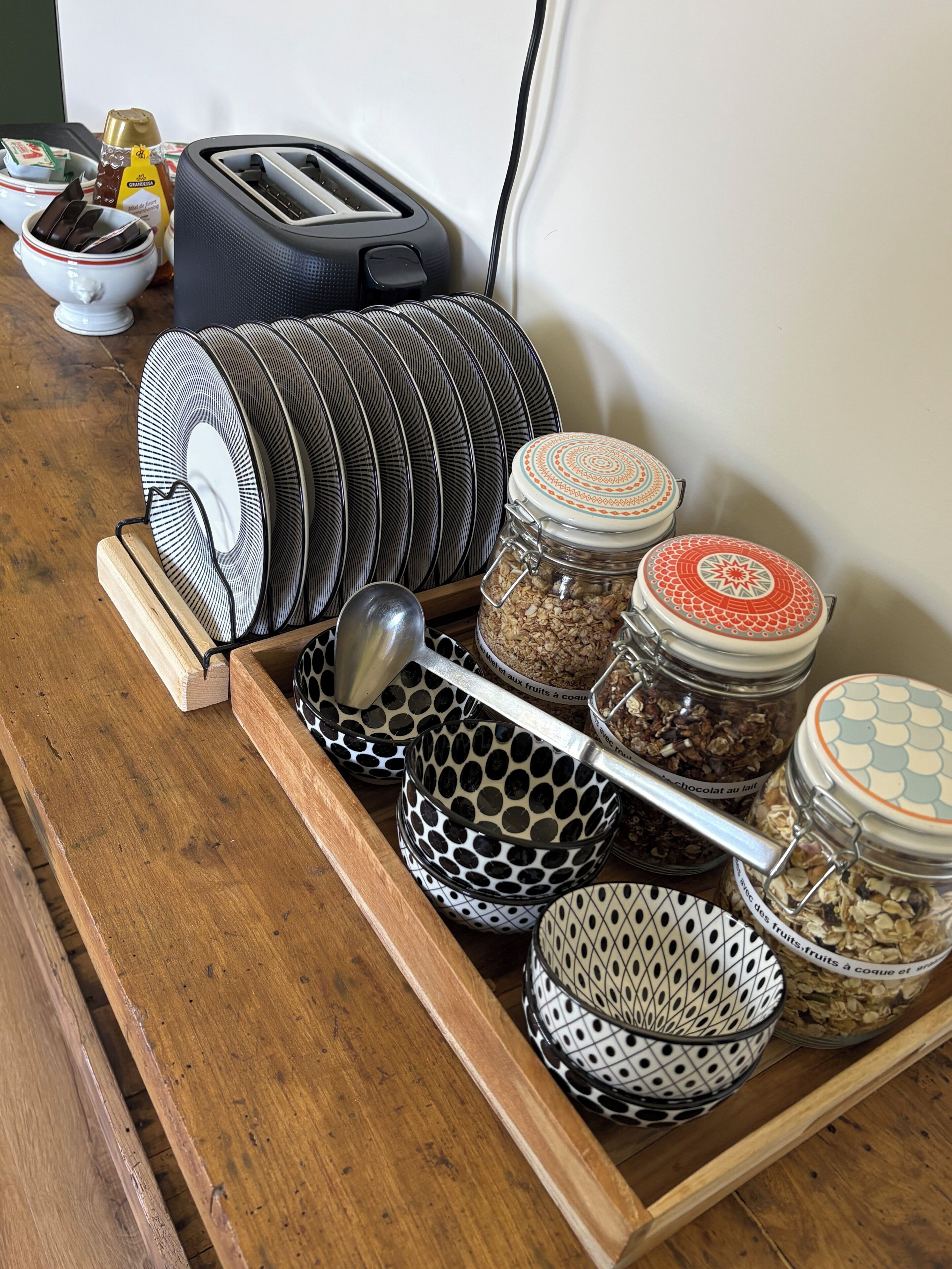 A kitchen counter with a toaster, a jar of honey, and a tray with various bowls and jars.