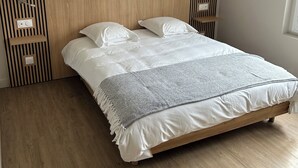 A bedroom with a wooden headboard, a bed with white bedding, and a window on the right. - Hôtel L'Escale des Hayons (Esclavelles)