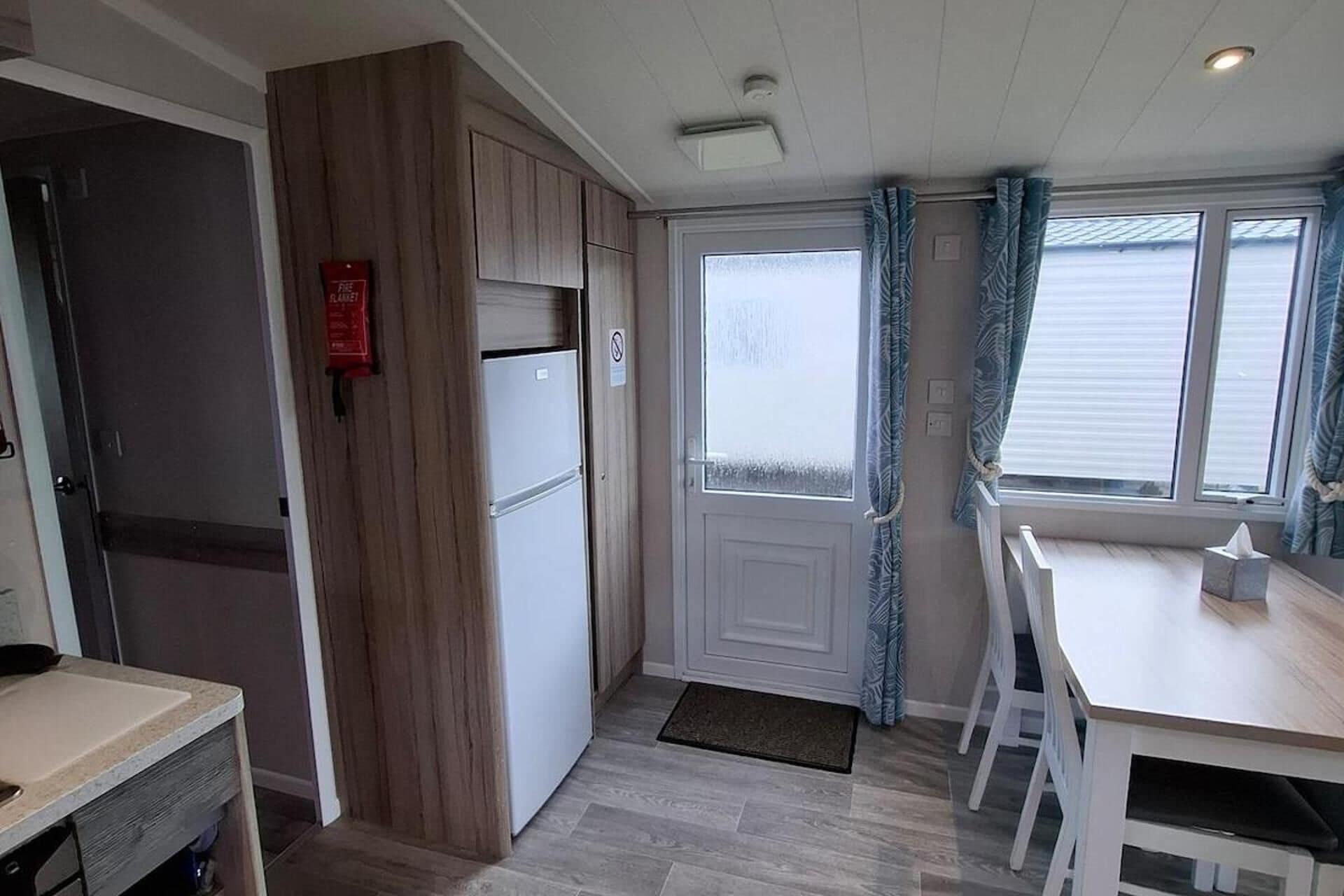 Eine kleine Küche mit Kühlschrank, Spüle und einem Essbereich mit Stühlen.
