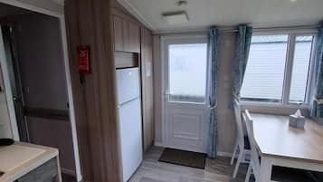 A compact kitchen with a refrigerator, a sink, and a dining area with chairs.