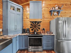 A kitchen with wooden walls, a stove, a refrigerator, and a dartboard. - New Cabin w/view|Hot tub|Himalayan Salt Room|Walk to Downtown Gatlnburg (GATLINBURG)
