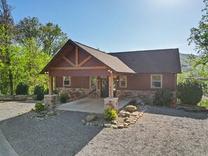 A lodge with a stone foundation, a wooden porch, and a gravel driveway. - New Cabin w/view|Hot tub|Himalayan Salt Room|Walk to Downtown Gatlnburg (GATLINBURG)