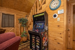 A wooden interior with a pinball machine, a clock, and a thermostat. - Hot Tub | Fireplace | Multicade | Mountain Views (Sevierville)