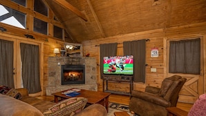 Ein gemütliches Blockhaus mit Kamin, Holzwänden, Fernseher und Ledermöbeln.