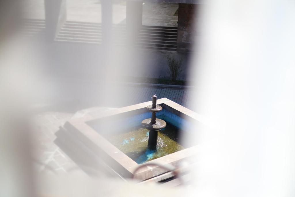 Een hottub met een centrale paal en een rechthoekig frame, omringd door een betegeld terras.