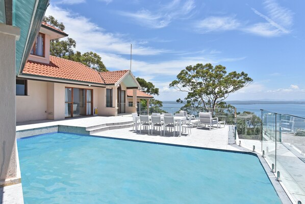 A swimming pool with lounge chairs and a view of the sea.