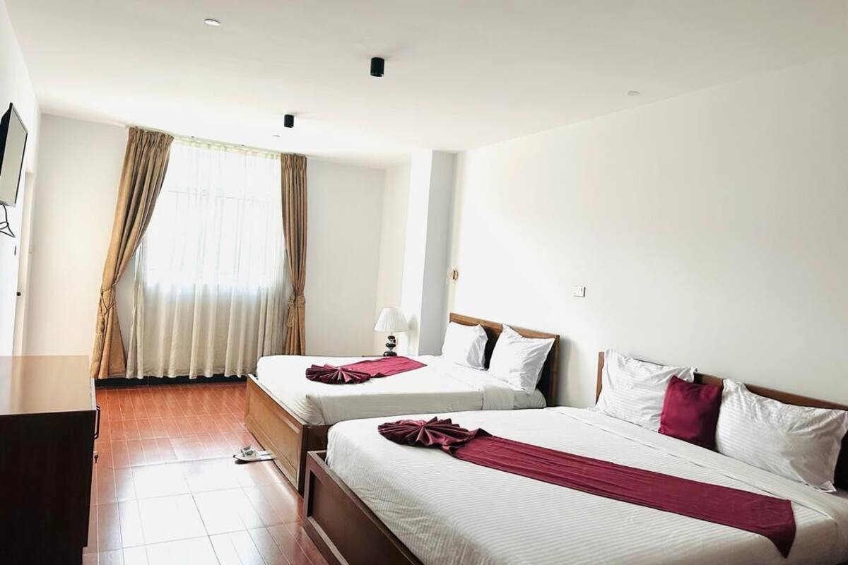 Una habitación de hotel con dos camas, un televisor y una ventana con cortinas.