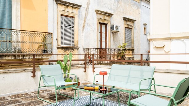 A balcony with green metal chairs, a glass table, and a patterned rug. - Apartment 'L'angolo Del Teatro' with Private Terrace and Air Conditioning (Galatone)