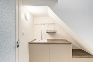 A modern bathroom with a sink, a towel rack, and a shower area.