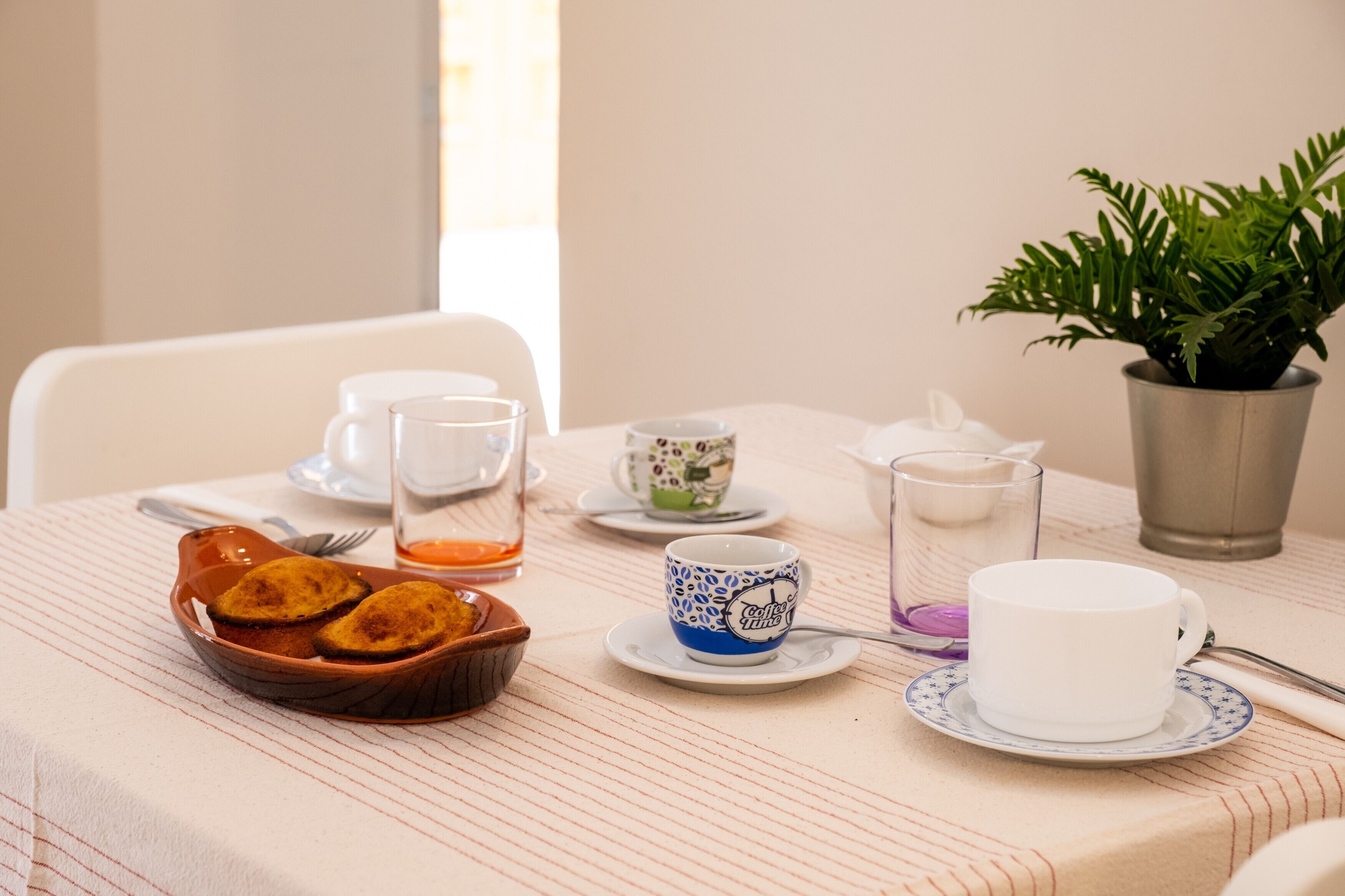 A table set with a cup, saucer, glass, and a bowl of food.