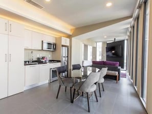 A modern kitchen with white cabinets, stainless steel appliances, and a dining area with a glass table and chairs. - Superior Suite (Ciudad de México)