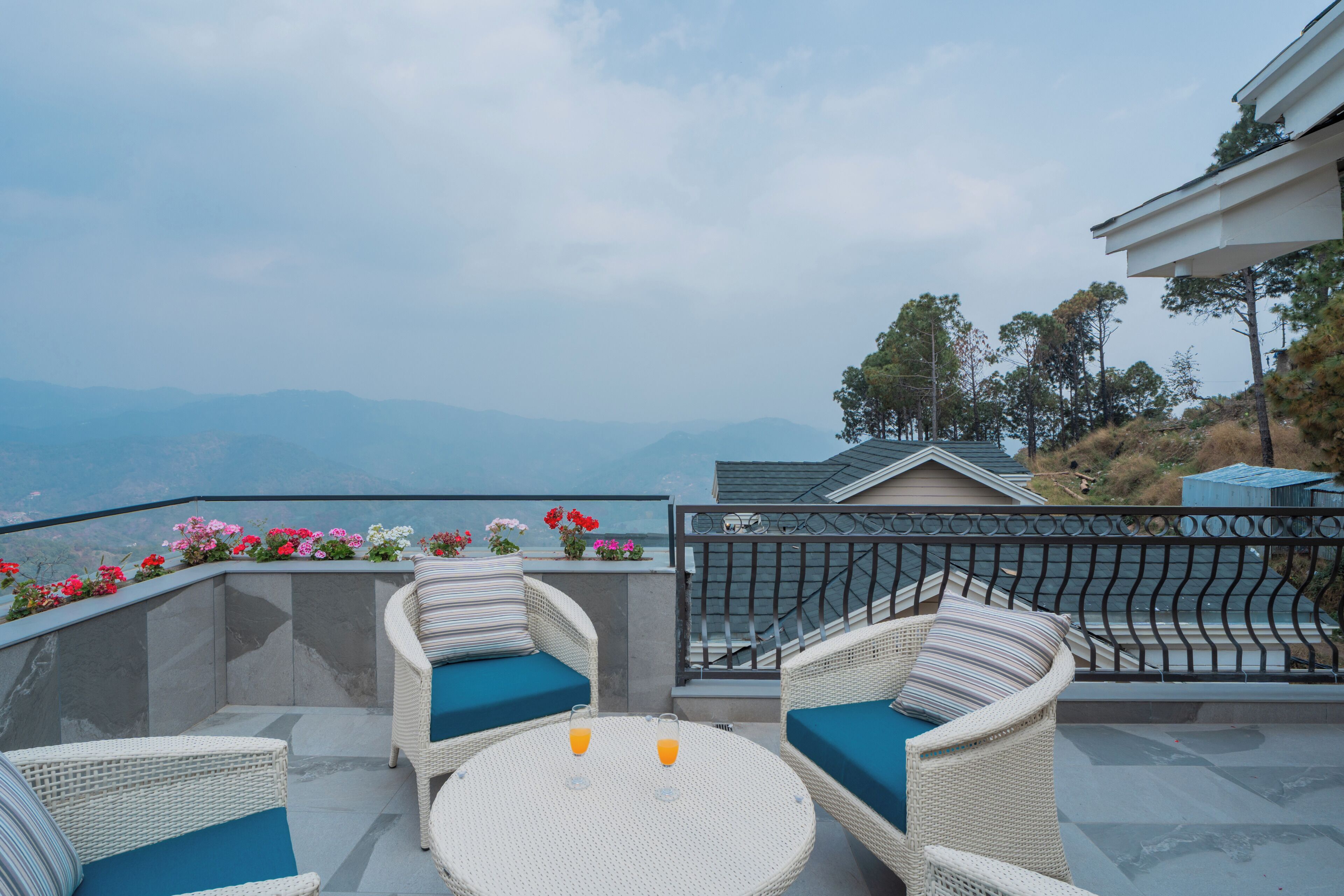 Eine Terrasse mit Korbmöbeln, einem runden Tisch und Bergblick.