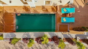 An outdoor swimming pool with wooden deck, two lounge chairs, and a small table. - ELIVAAS privé The Royce Orchid 4BHK (Kasauli)