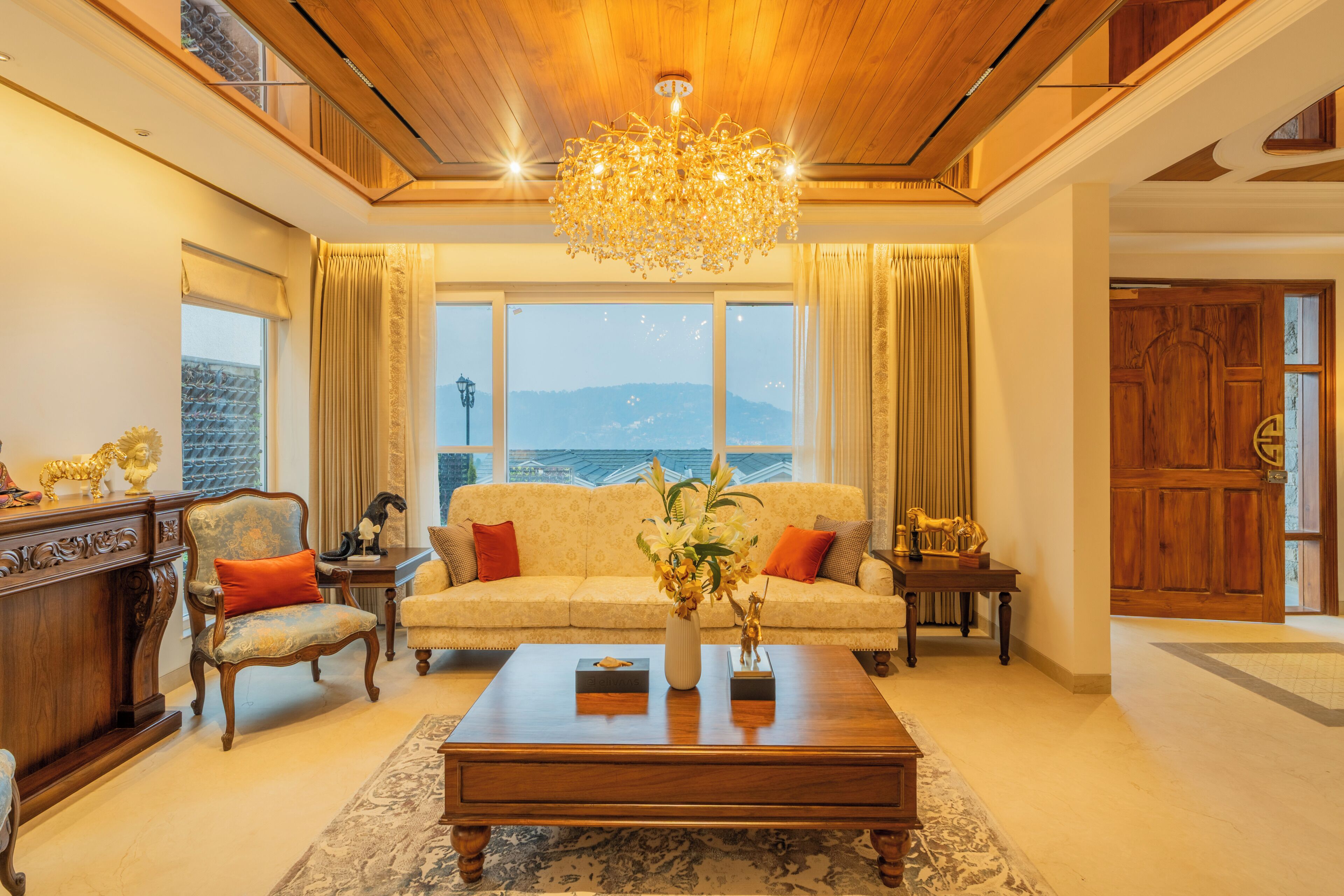 A spacious living room with a large window, a chandelier, a sofa, and a coffee table.