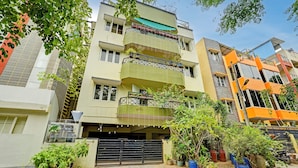 A multi-story residential building with balconies, a garage, and potted plants. - Alaya Stays Saffron Breeze Apartment  (Bengaluru)