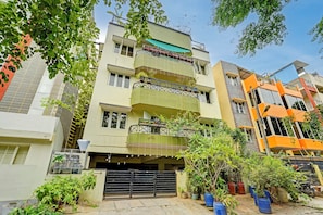 A multi-story residential building with balconies, a garage, and potted plants. - Alaya Stays Saffron Breeze Apartment  (Bengaluru)