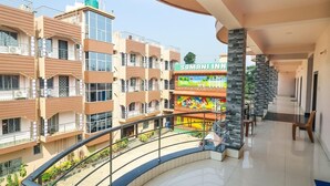 A multi-story building with balconies, a children's play area, and a stone pillar. - Somani Inn (Jhargram)