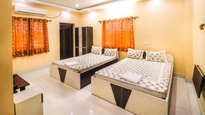 A bedroom with two beds, an air conditioning unit, a ceiling fan, and a wardrobe. - Somani Inn (Jhargram)