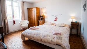 Una camera da letto con un letto, una sedia, un armadio, un comodino e una lampada.