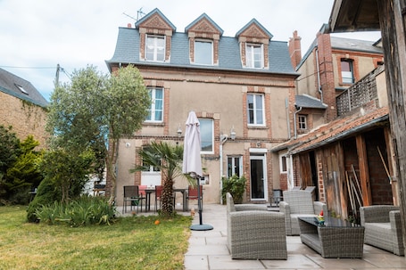 A brick house with a patio area, outdoor furniture, and a small garden.. Room with Private Bathroom in Dives/Cabourg