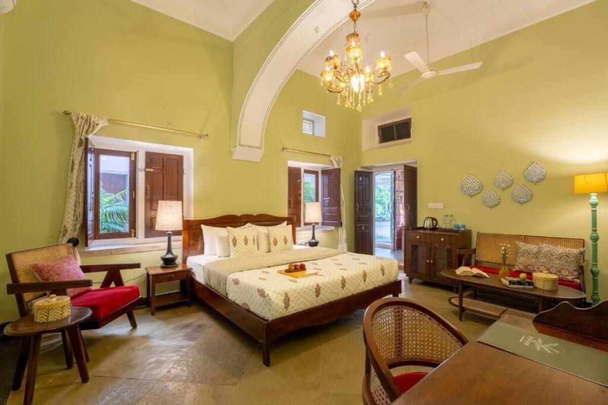 Una habitación con una cama, una silla, una mesa, una lámpara y un candelabro.