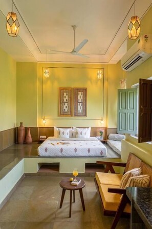 A bedroom with a bed, bedside tables, a sofa, a ceiling fan, and wall-mounted lights.