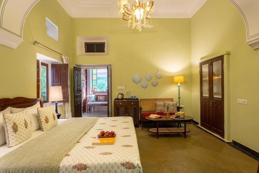 A bedroom with a bed, bedside table, lamp, and a view of a dining area.