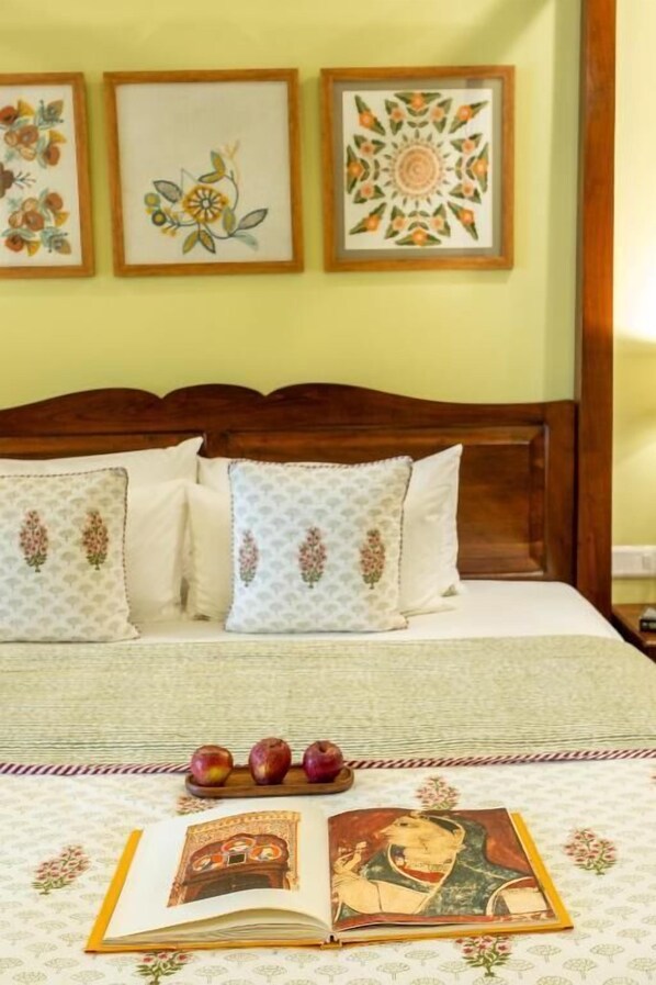A bed with patterned pillows, a wooden headboard, and a book with a picture on the bedspread. - Mukam at Kanakvilas (Jaipur)
