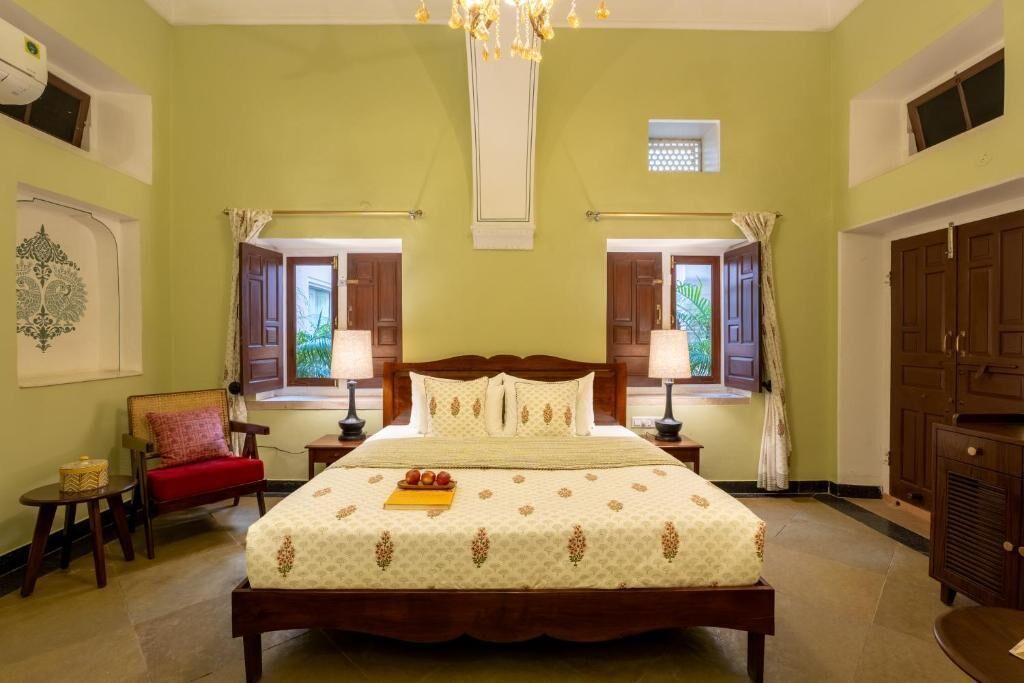 A bedroom with a large bed, two bedside tables, a chair, a wardrobe, and a window with curtains.