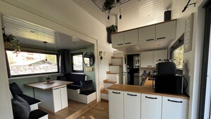 A compact kitchen with white cabinets, a wooden countertop, and a black coffee machine. - Cozy Tiny House "Spree-Maus" Family-friendly - only 50m to the Spree (Grünheide (Mark))