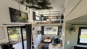 A compact, modern interior with a loft bed, a dining area, and a kitchen. - Cozy Tiny House "Spree-Maus" Family-friendly - only 50m to the Spree (Grünheide (Mark))
