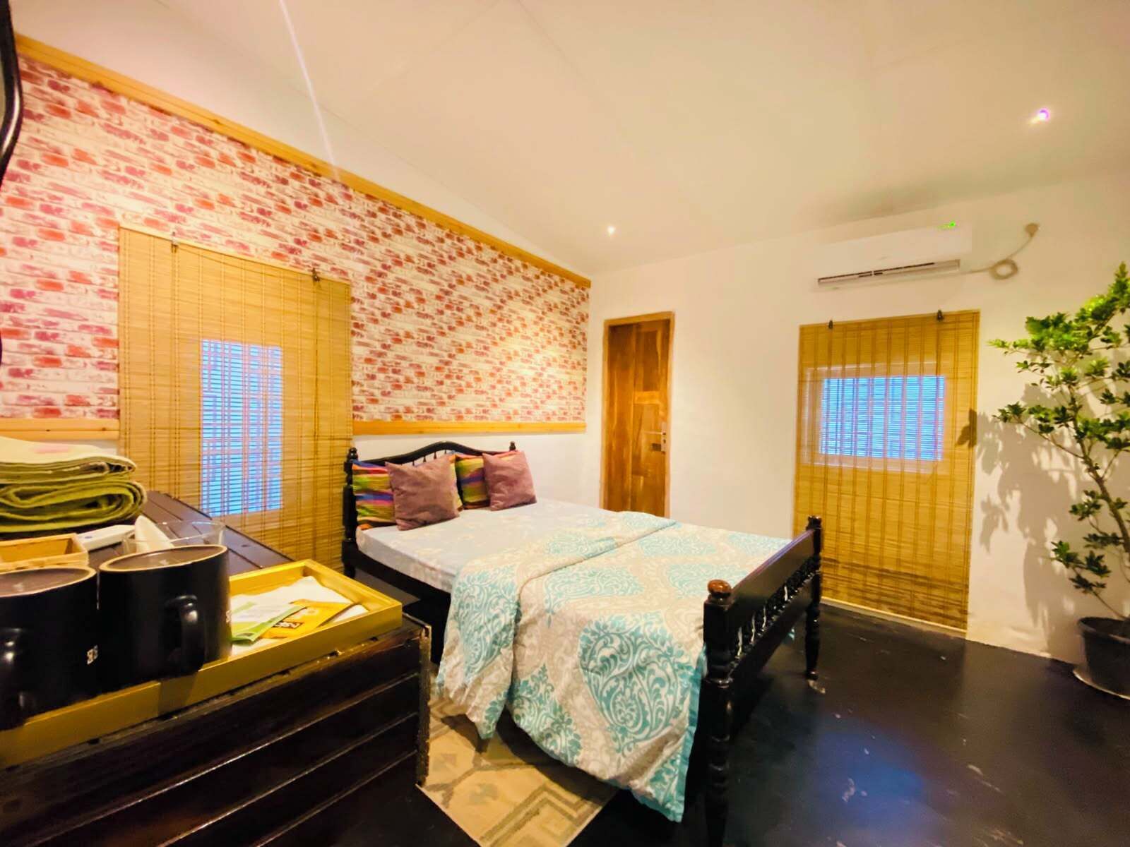 Un dormitorio con cama, mesita de noche con lámpara, ventana con persianas y aire acondicionado instalado en la pared.
