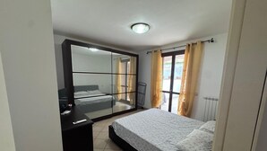 Een slaapkamer met een bed, een kledingkast, een bureau en een raam met gordijnen.