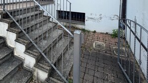 Een gebouw met een trap die naar een hoger gelegen deel leidt, een overdekt terras en een zichtbaar raam.