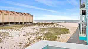 Une vue sur la plage, avec un immeuble doté de nombreux balcons et un chemin menant à la plage.
