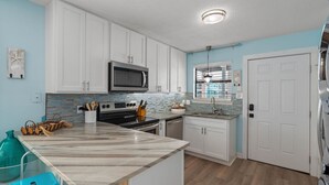 Une cuisine moderne avec des armoires blanches, un four à micro-ondes, une cuisinière et un évier.