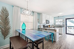 A modern kitchen with a central island, white cabinets, and a large window. - Coastal Condo Steps From the Beach (Gulf Shores)