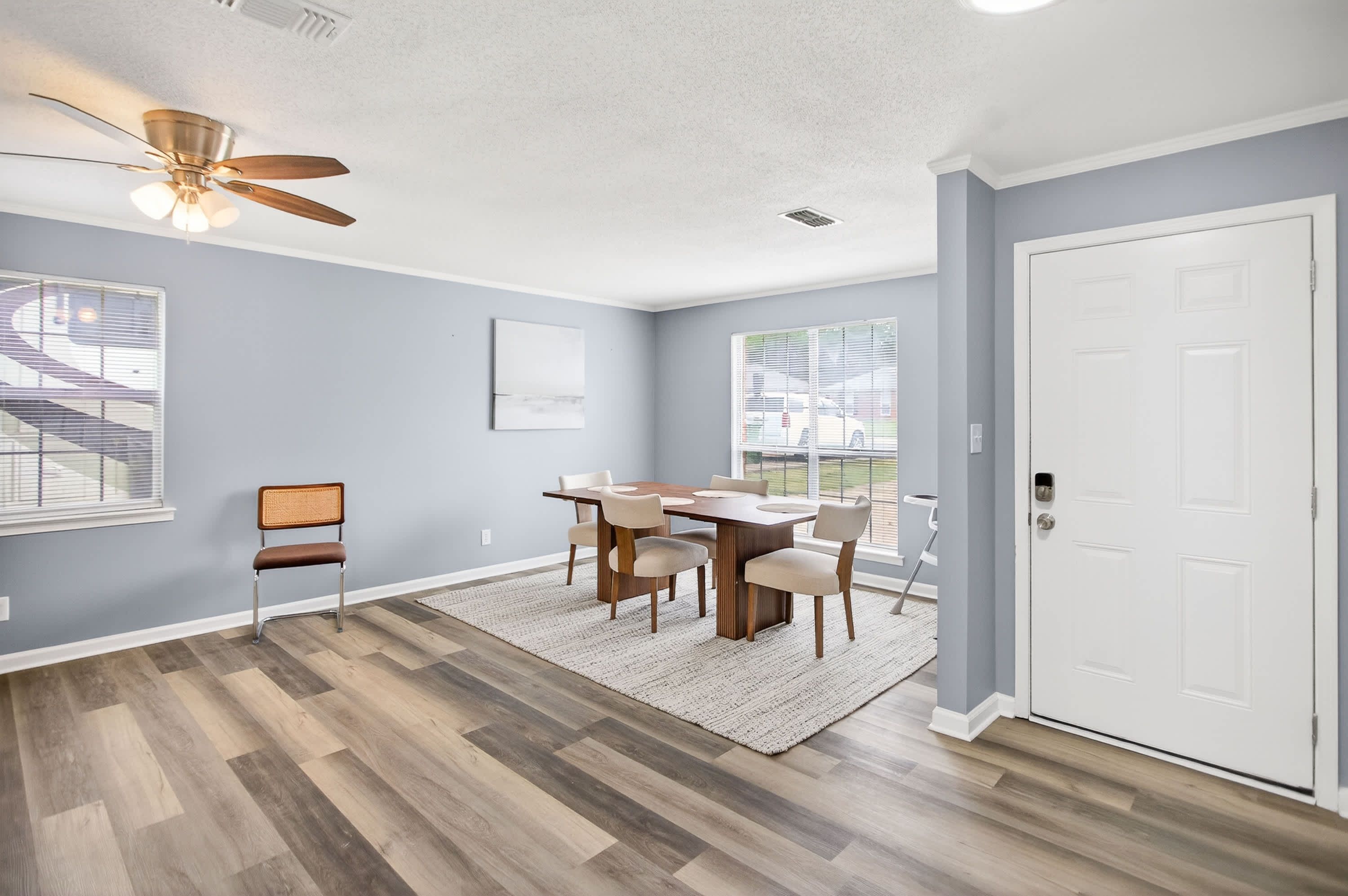 A dining area with a table and chairs, a ceiling fan, and a view of the outside.