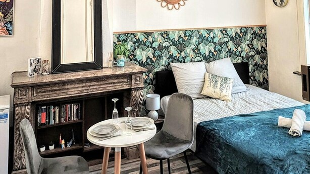 Une chambre d’hôtel comprenant un lit, un bureau avec un miroir, une table ronde avec des chaises et une bibliothèque.
