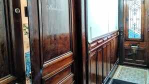 Une porte en bois, dotée d’une poignée en métal et d’un panneau de verre orné de motifs en métal.