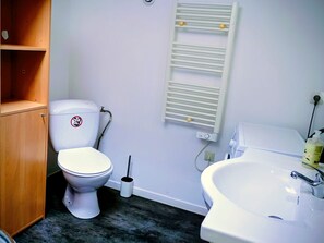 Een badkamer met een toilet, een wastafel, een handdoekhouder en een houten kastje.